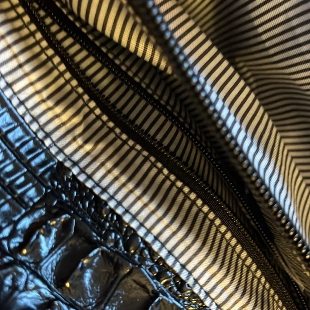 No brand black faux leather purse with black tassel and zippers for design.
